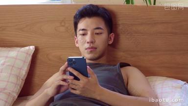 青年男人躺在床上看手机